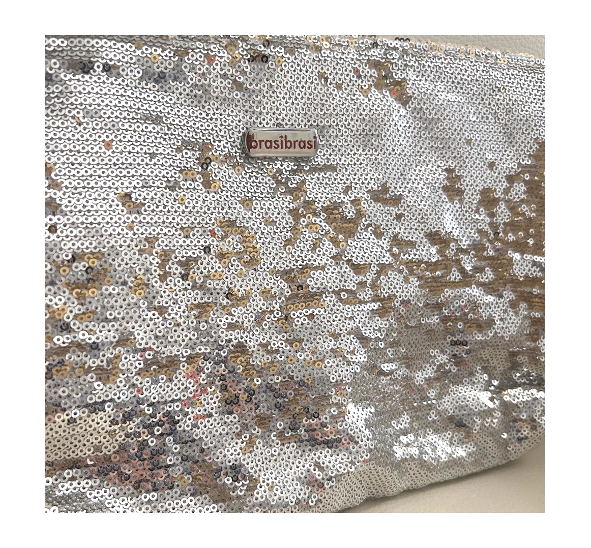 Nahaufnahme einer brasibrasi Clutch oder Kulturtasche, vollständig mit schimmernden Wendepailletten bedeckt. Die Pailletten wechseln zwischen Silber und Gold, viele goldene Seiten sichtbar, für ein lebendiges Glitzermuster. Logo oben links.
